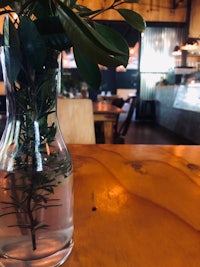 a vase with a plant in it sitting on a table in a restaurant