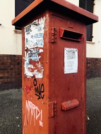a red post box with graffiti on it