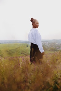 a woman in a white shirt standing in a field